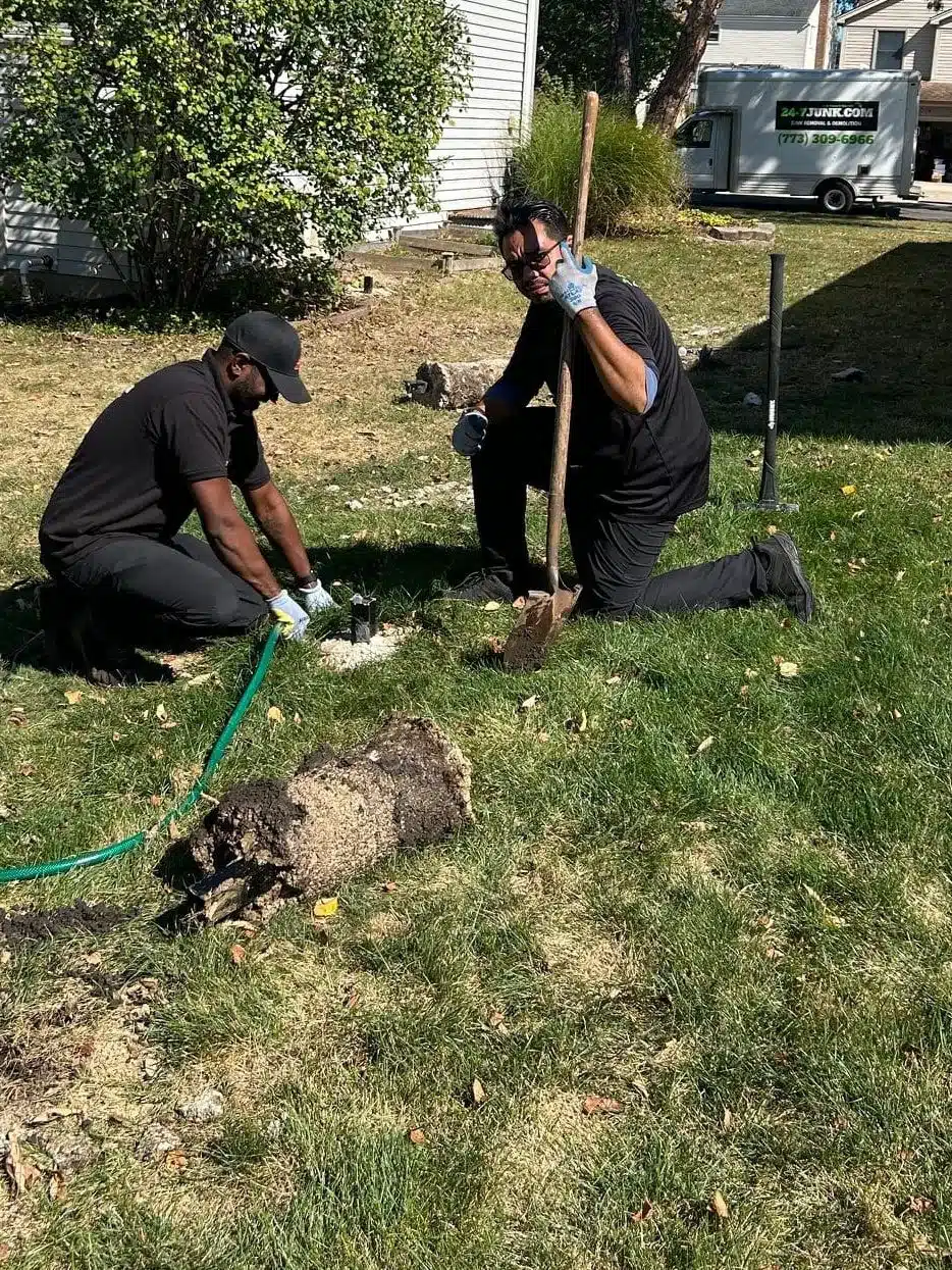 24-7JUNK.COM team efficiently removing a fence post during a fence removal project near Schaumburg, IL, showcasing professional junk removal services in the local area.