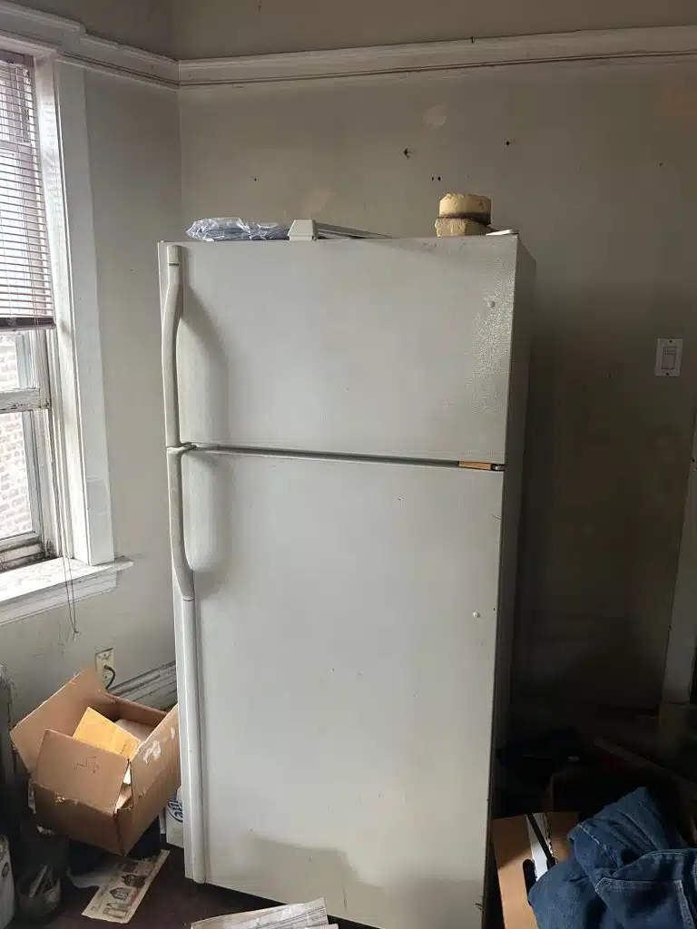 Refrigerator standing up against a window and wall